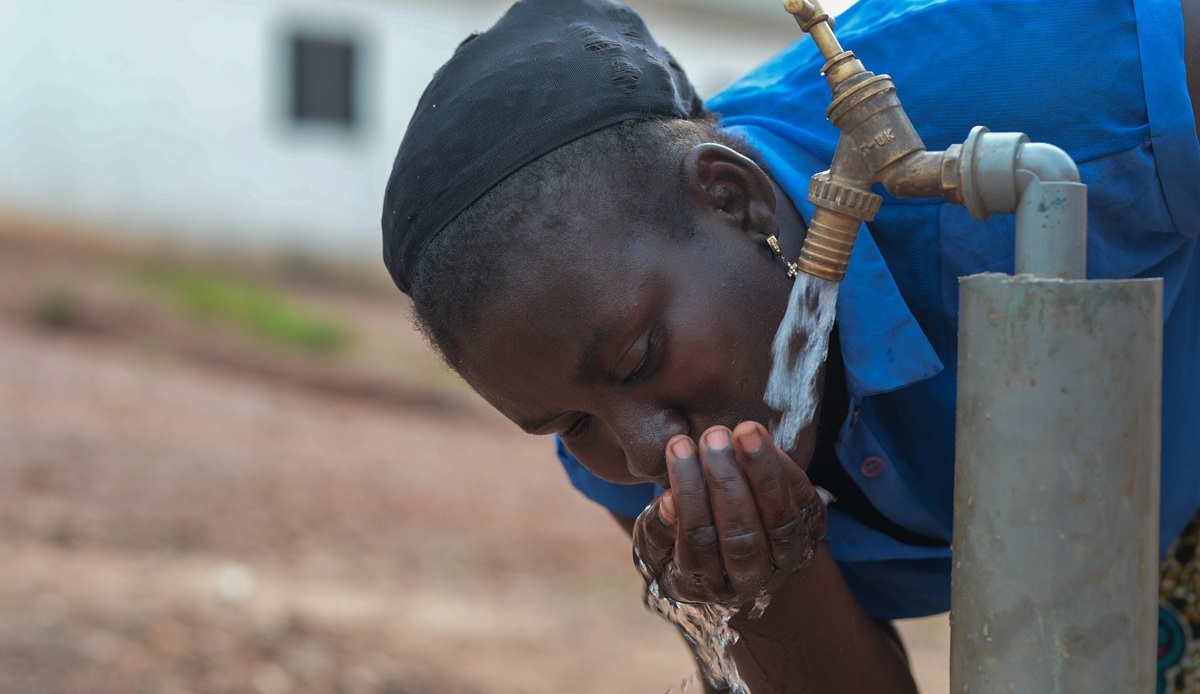 Girl in blue dress drinking water from tap